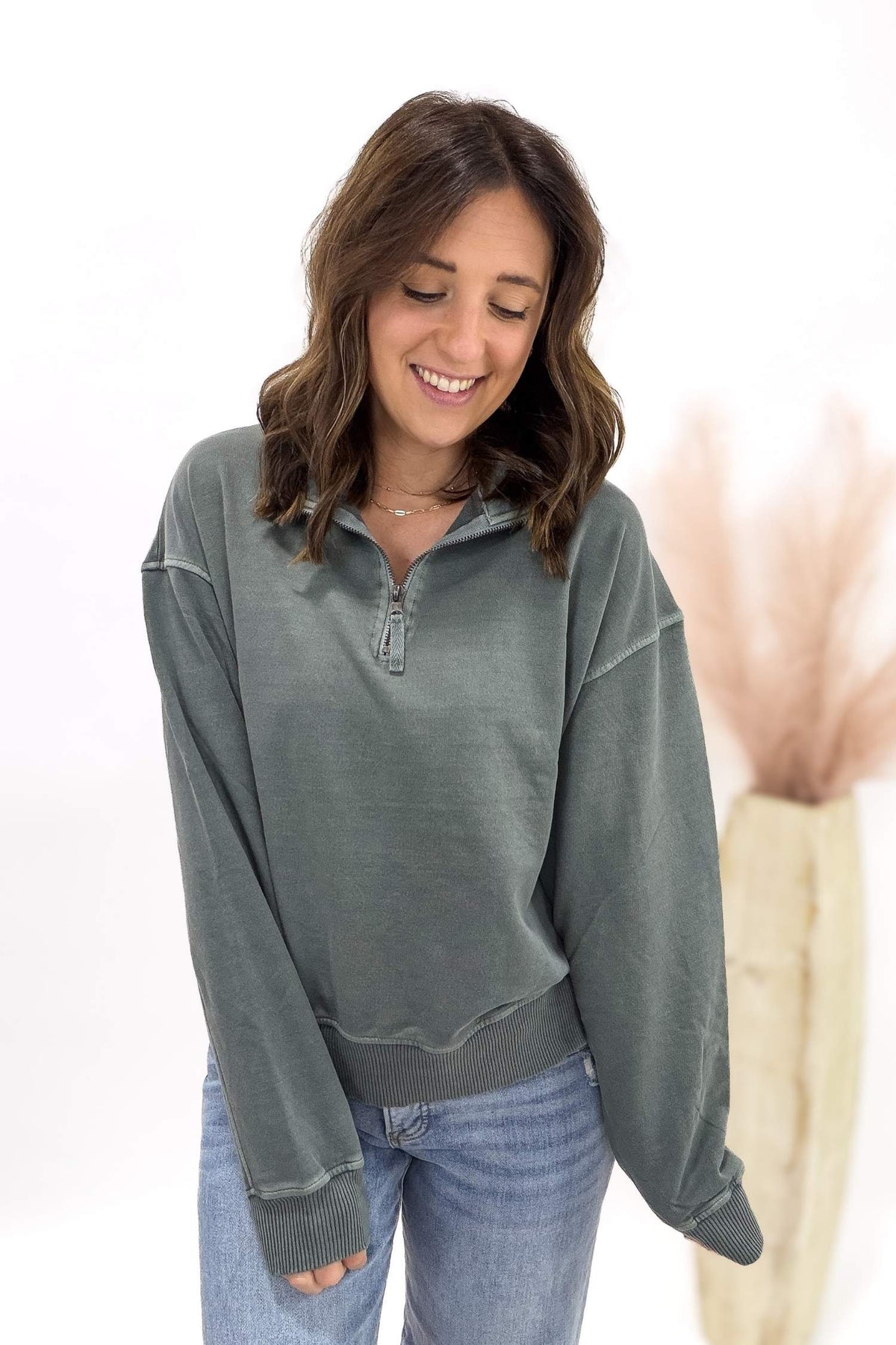 Woman wearing a jade long-sleeve shirt with a zipper on a white background