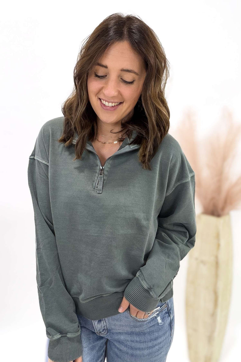 Woman wearing a jade pullover with a zipper on a white background