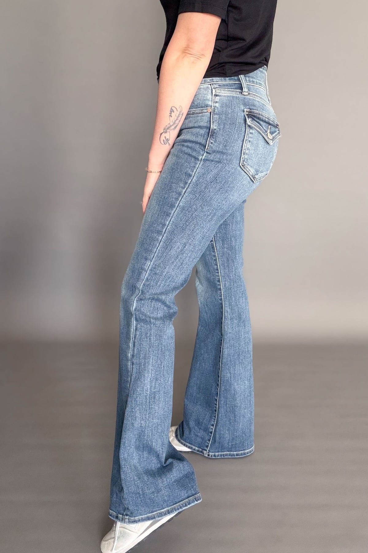 Person wearing blue flared jeans on a plain background