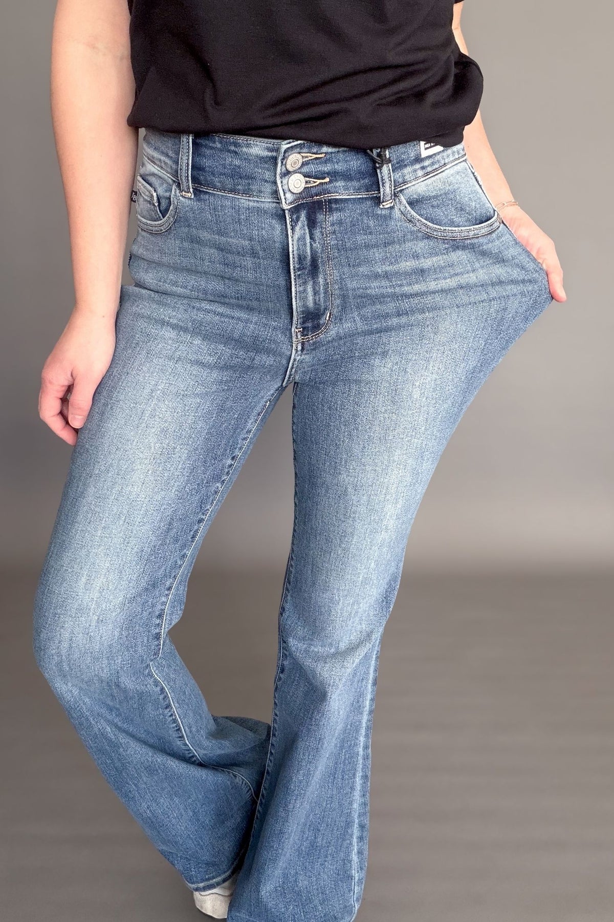 Person wearing blue flared jeans showing the stretch on a gray background