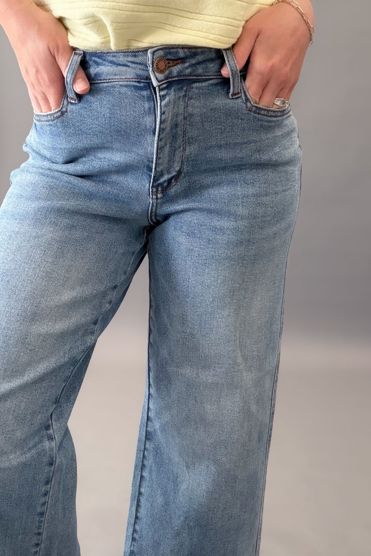 Person wearing blue jeans with a neutral background