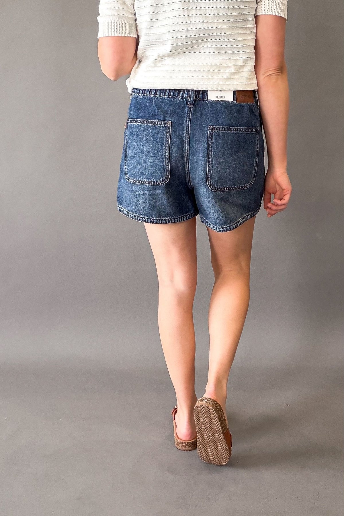 Woman wearing Judy Blue high waist boxer shorts showing back details with pockets.