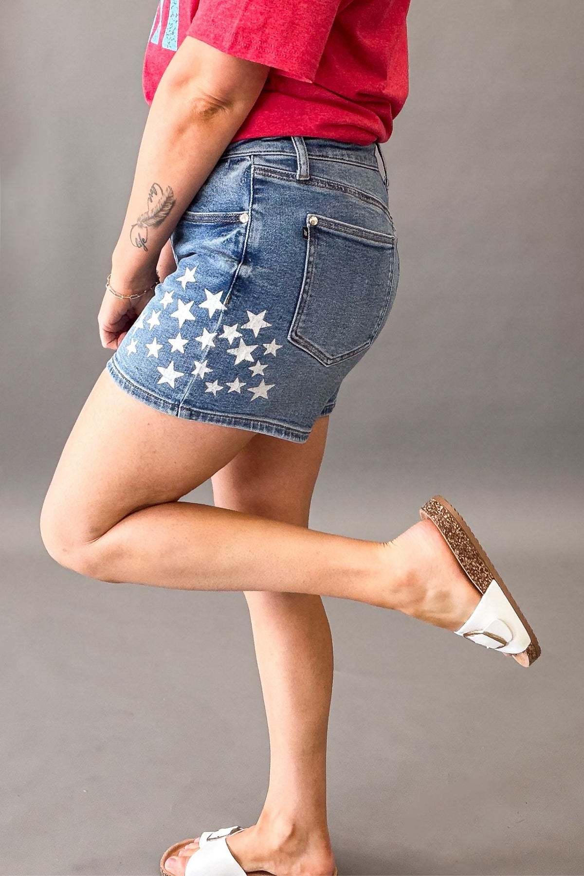 Woman wearing Judy Blue high waist slim denim shorts with white star spatter detail and patriotic summer outfit