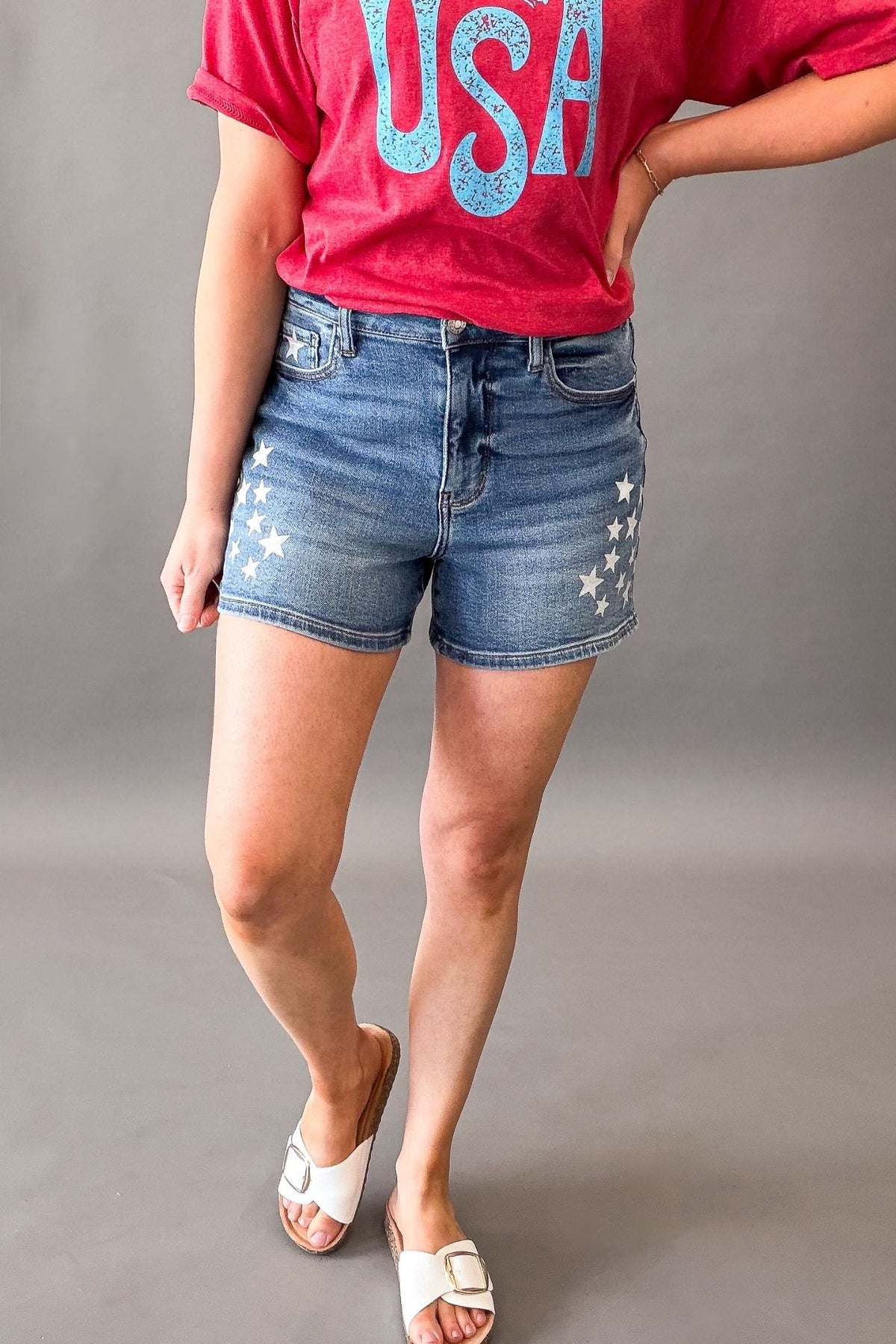 Woman wearing Judy Blue high waist slim denim shorts with white star spatter detail and patriotic summer outfit