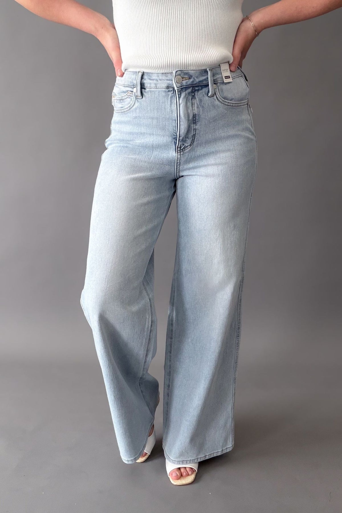 woman wearing a pair of judy blue light wash wide leg jeans on a grey background