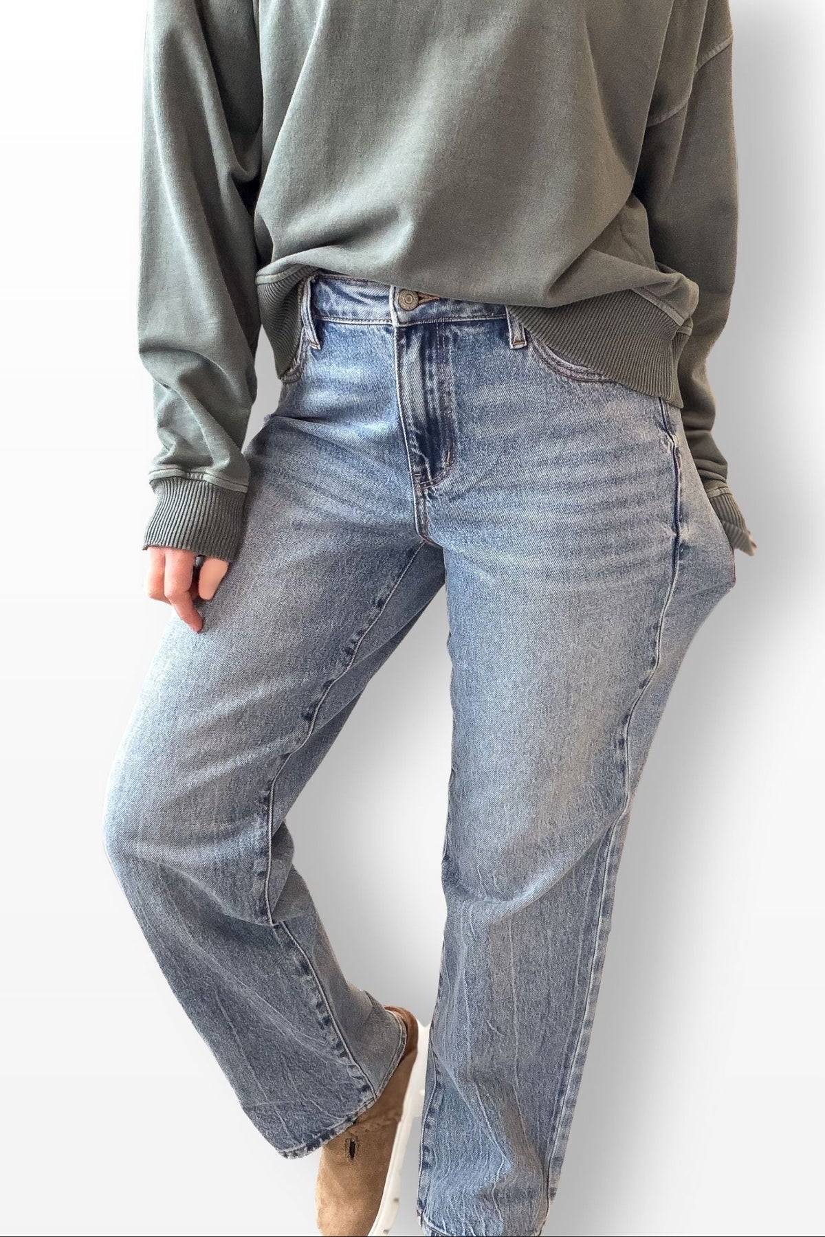 Person wearing blue jeans and a green sweater on a white background