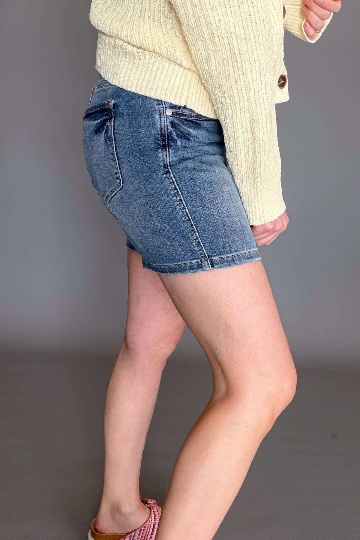 Judy Blue mid rise tummy control mid length denim shorts on model side view
