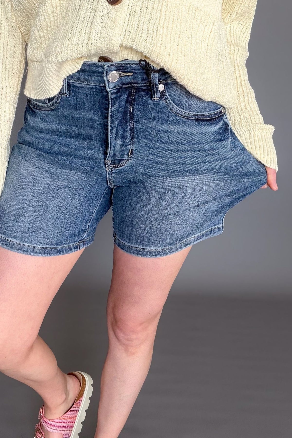 Judy Blue mid rise tummy control mid length denim shorts on model showing stretch