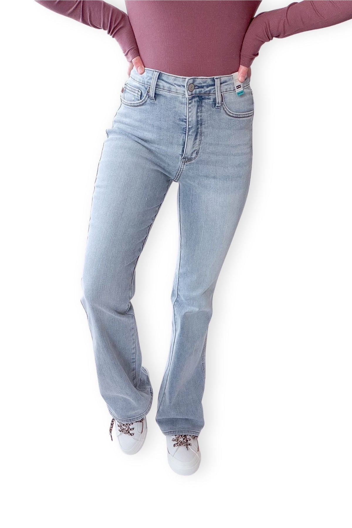 Person wearing light blue jeans and a maroon top on a white background