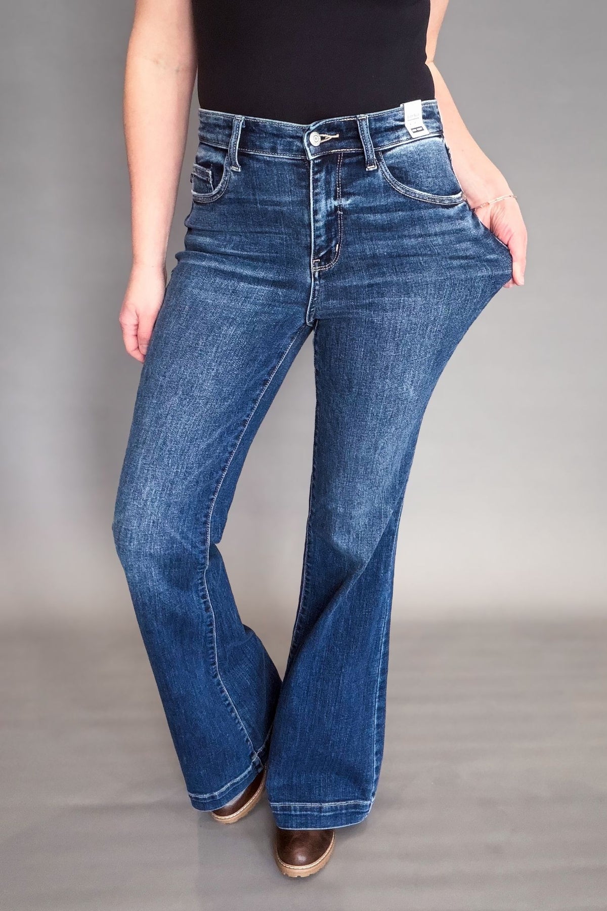 Person wearing blue flared jeans on a gray background