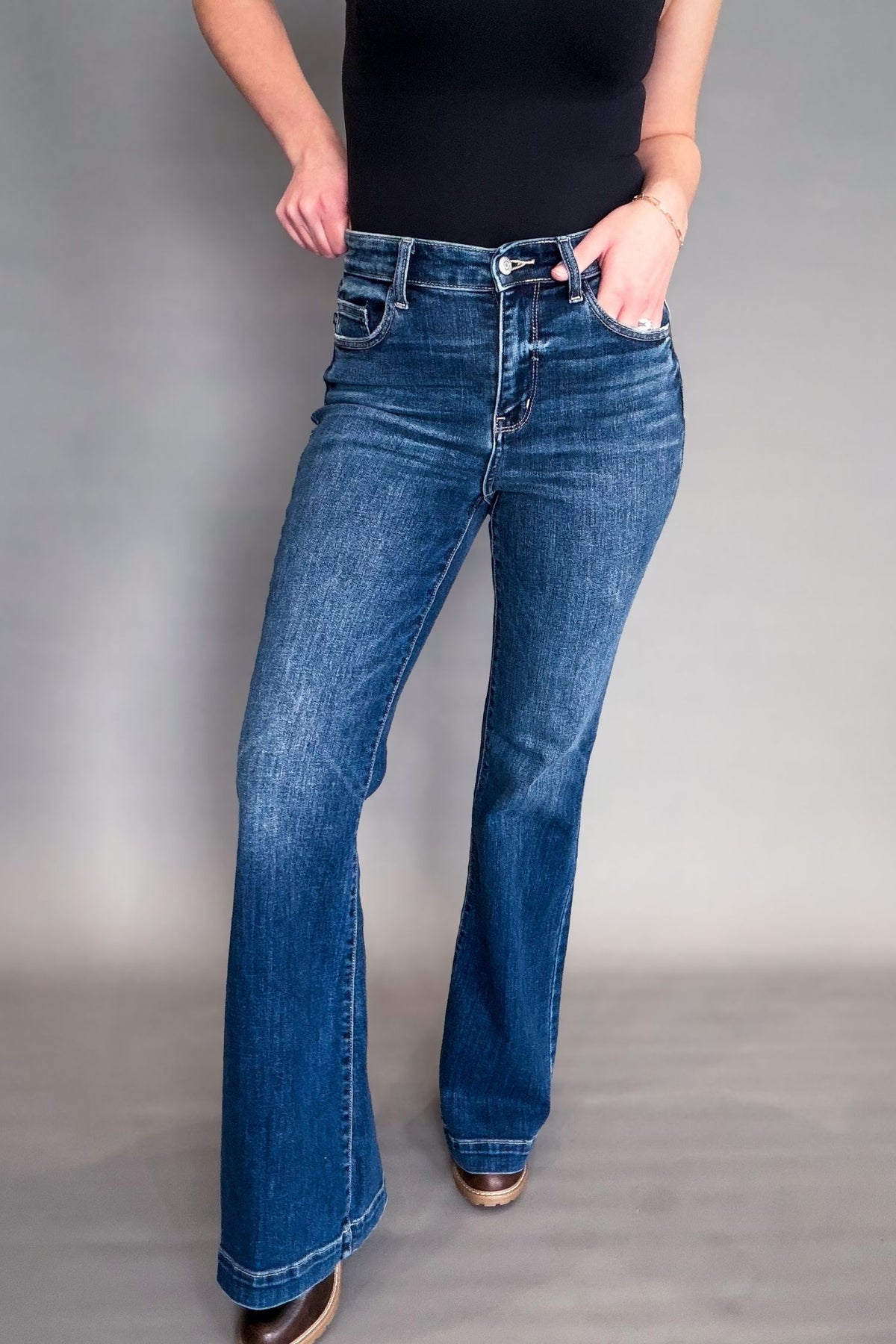 Person wearing blue flared jeans on a gray background