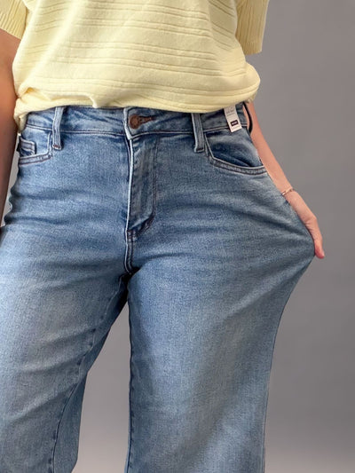 Person wearing judy blue jeans and a yellow top on a gray background