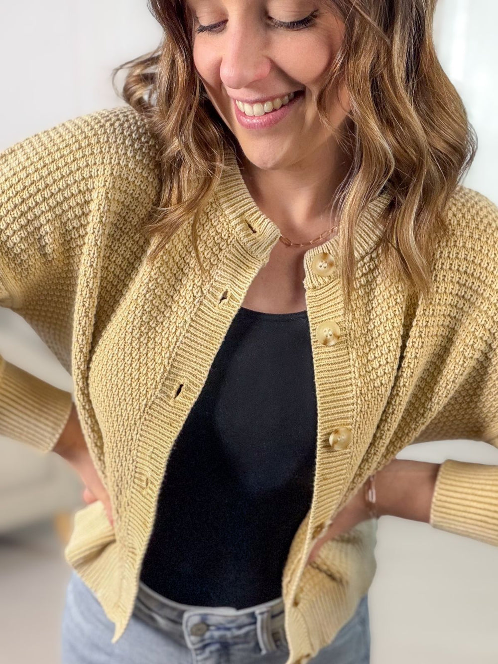 Woman wearing a yellow knitted cardigan over a black top.