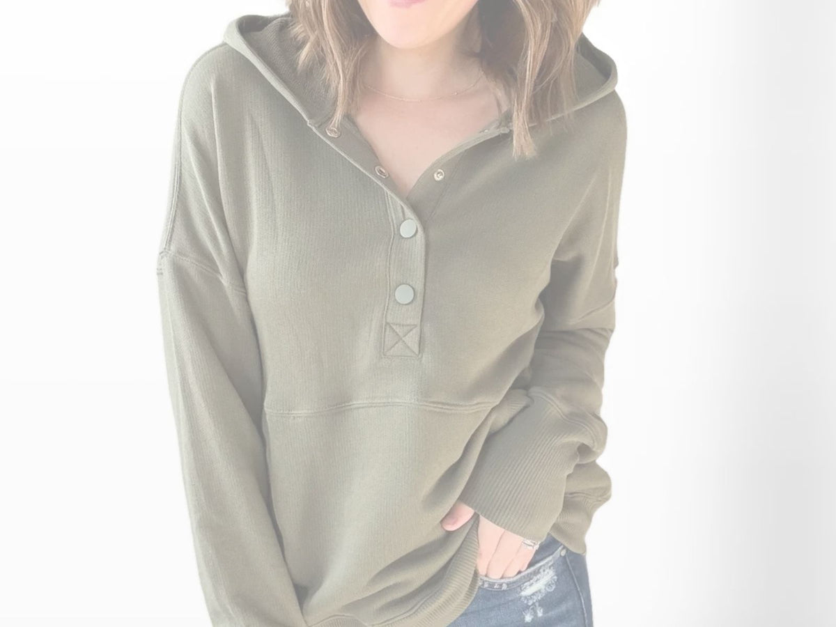 Person wearing a green hoodie with button details on a white background