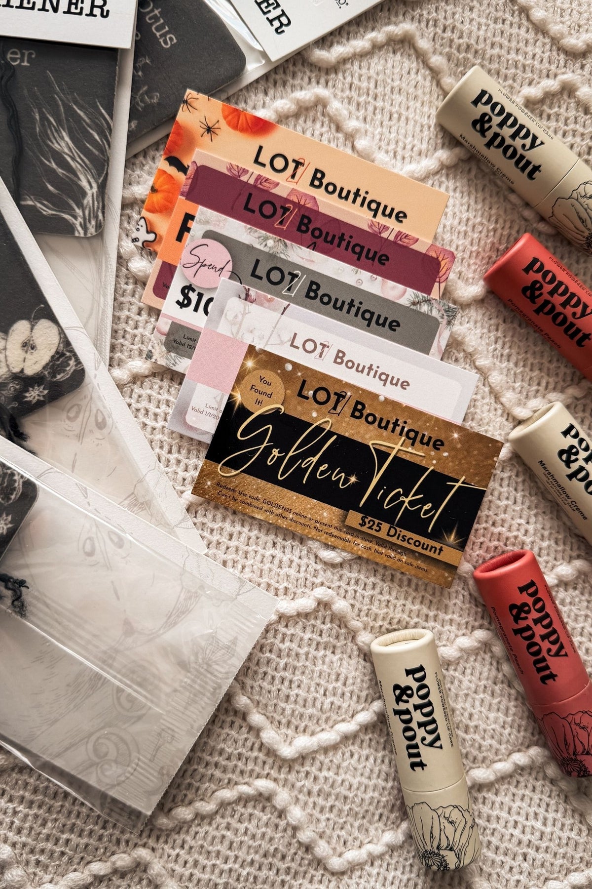 Collection of 'LOT Boutique' and 'poppy & pop' product packaging on a textured surface.