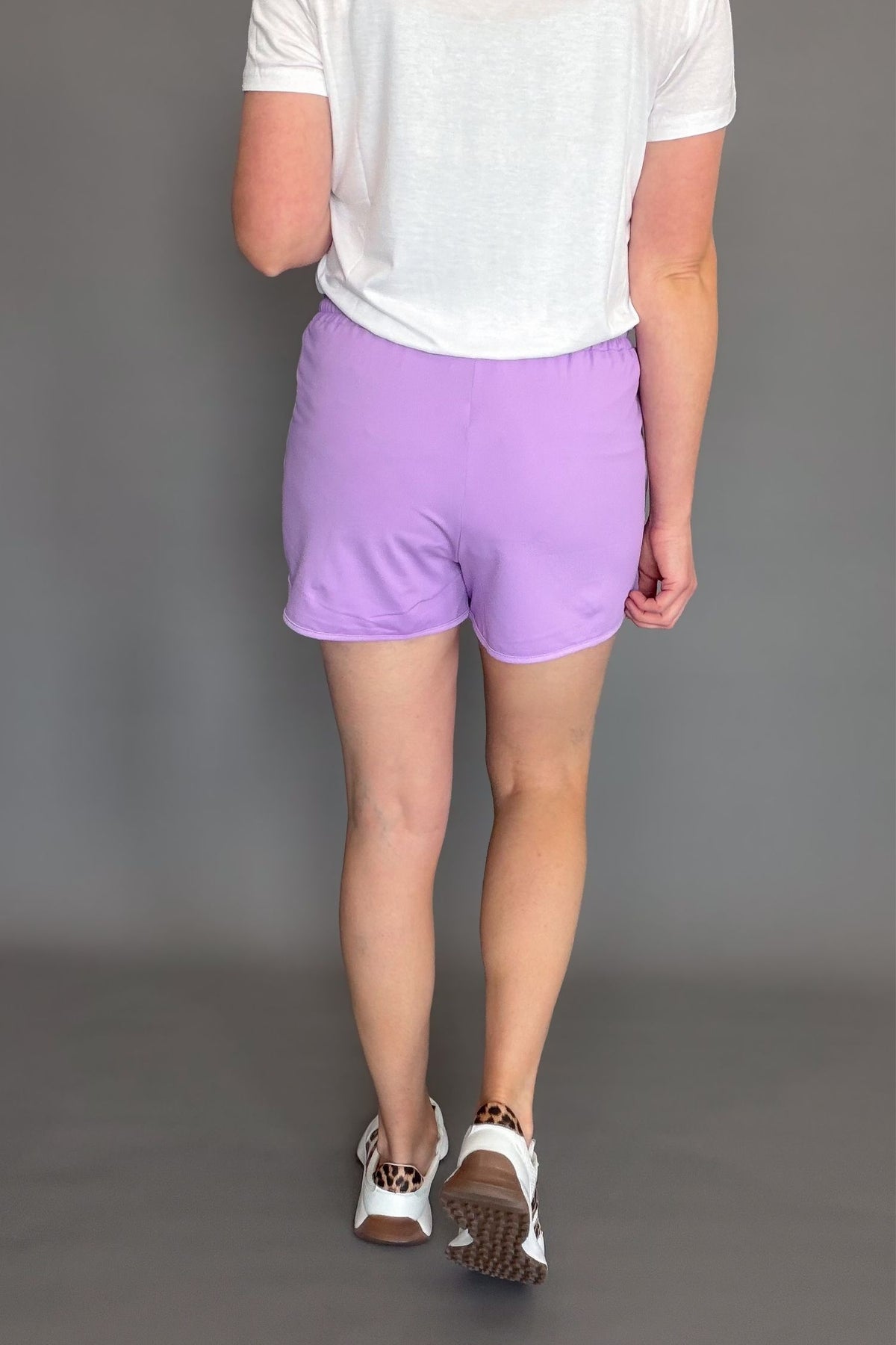 lavender soft stretchy everyday shorts with drawstring waist and pockets styled with sneakers.