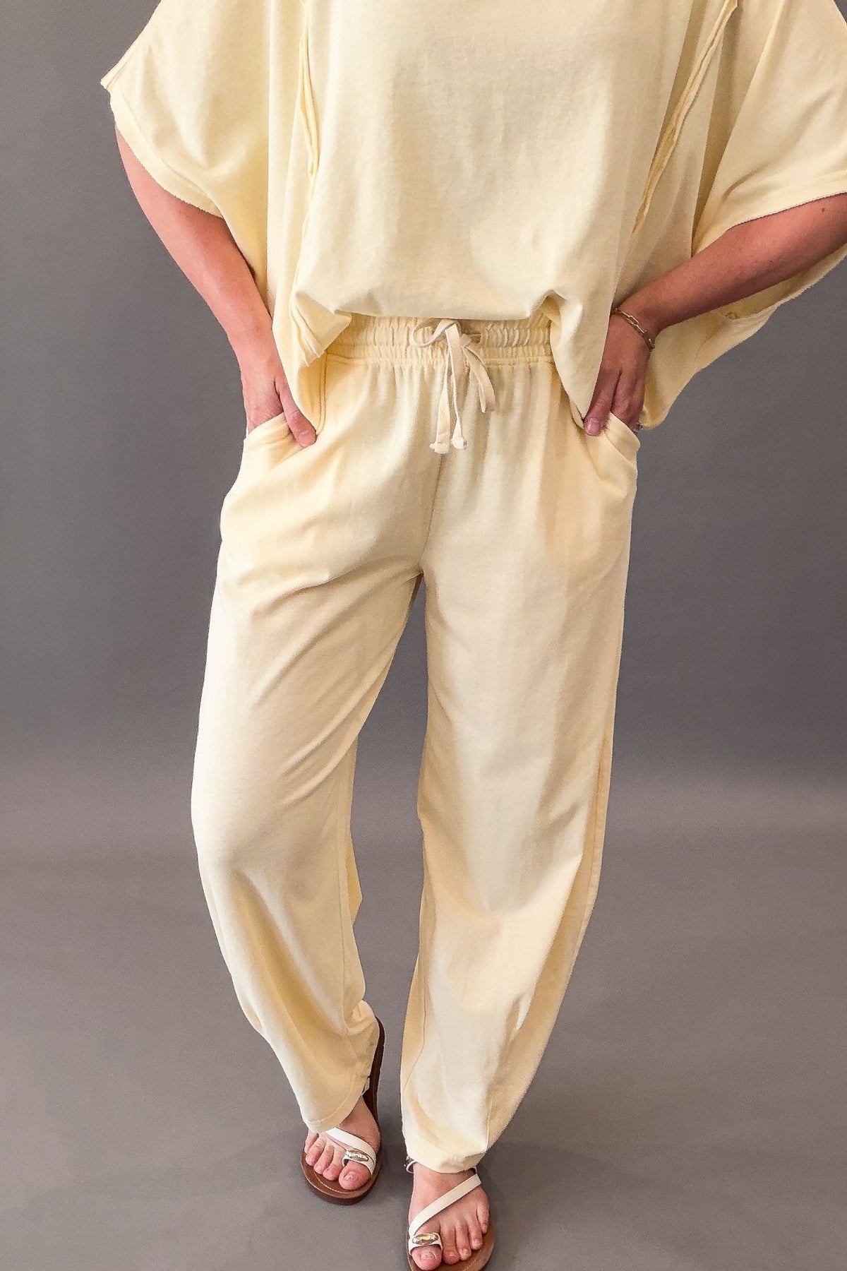 Person wearing a light yellow outfit with a drawstring top and pants on a gray background