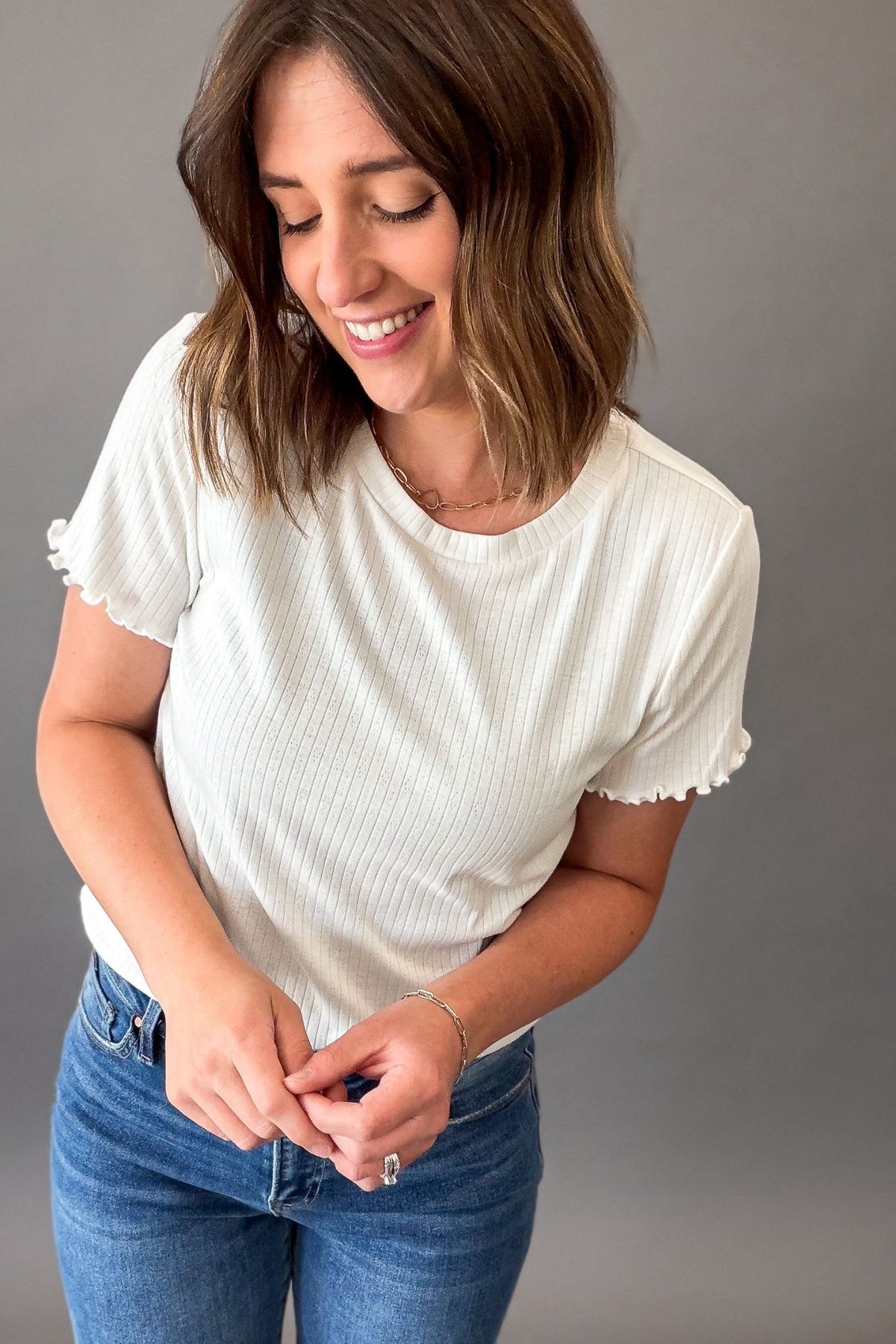 Woman wearing a white short sleeve ribbed tee with lettuce sleeve edge detail