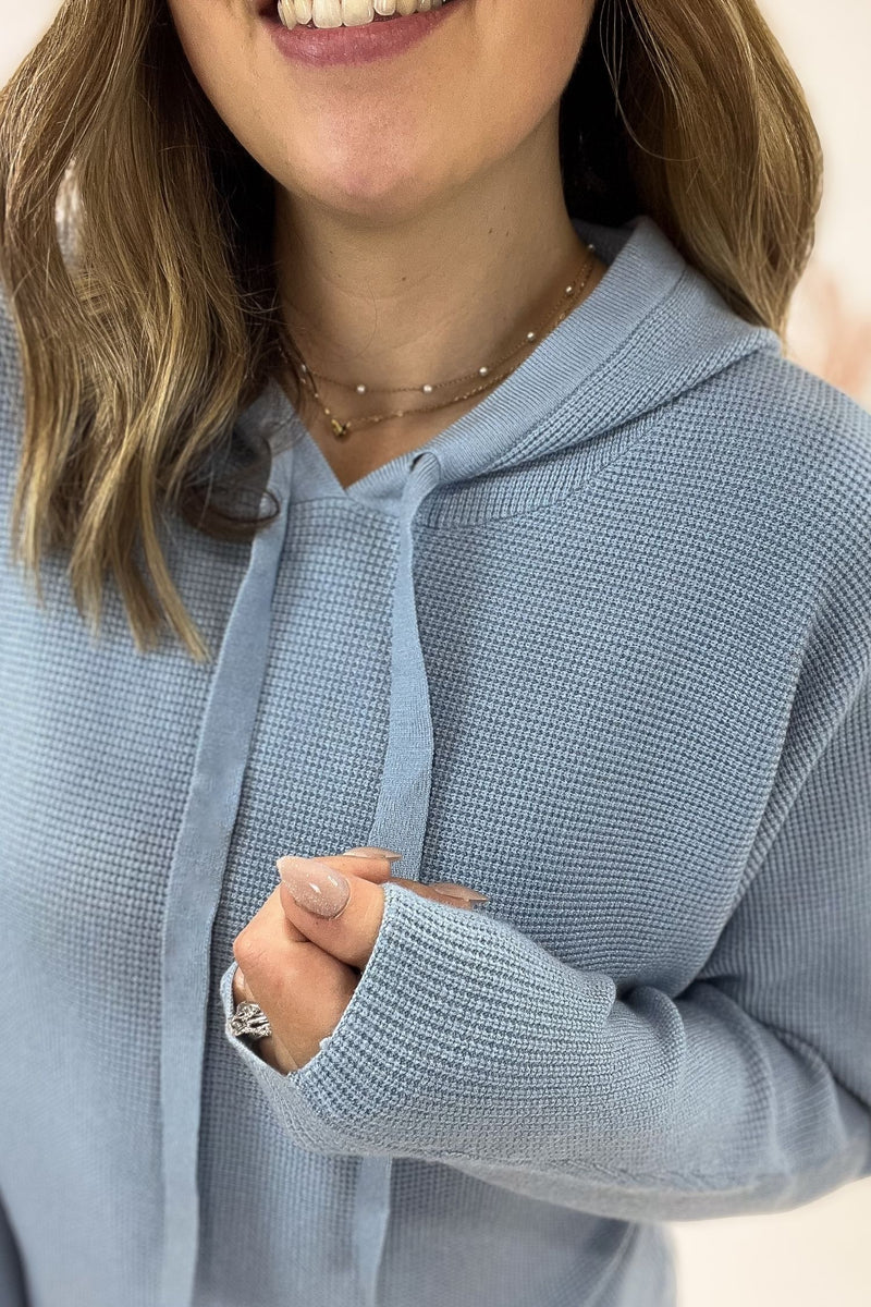 Person wearing a light blue hoodie with a neutral background