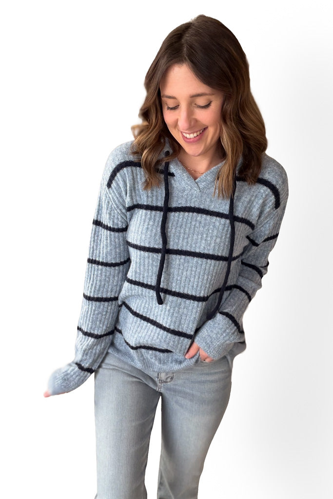 Woman wearing a light blue sweater with dark blue stripes on a white background