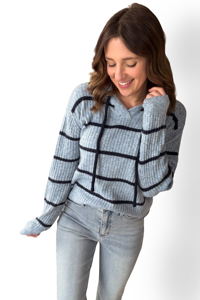 Woman wearing a light blue sweater with dark navy striped pattern on a white background