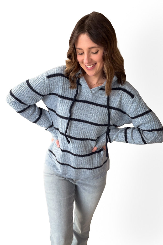 Woman wearing a light blue sweater with dark blue stripes on a white background