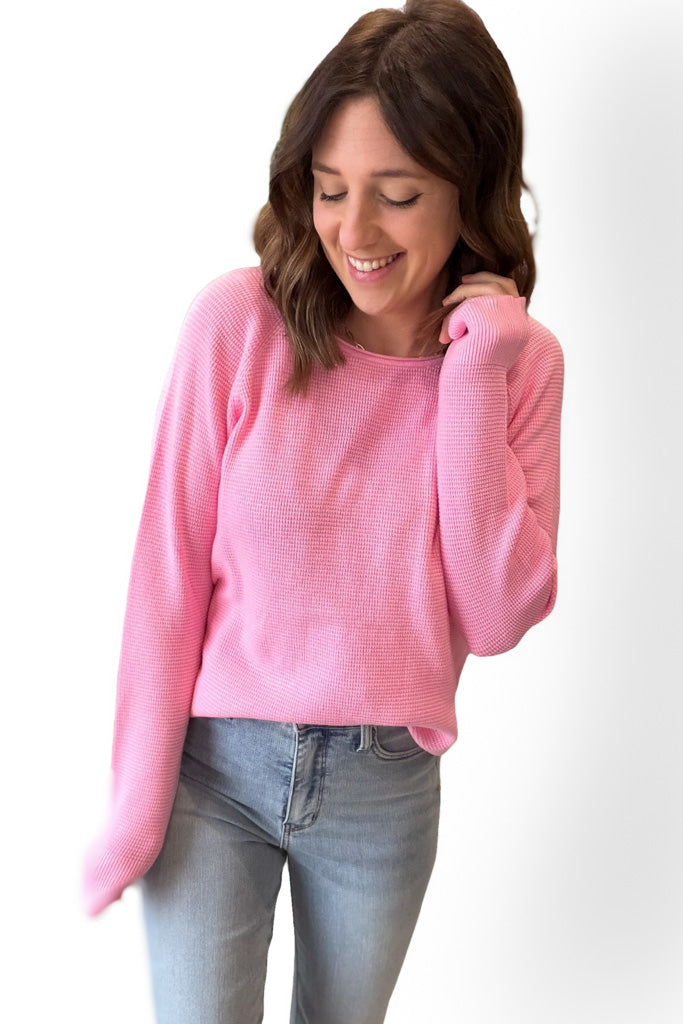 Woman wearing a pink sweater and blue jeans on a white background