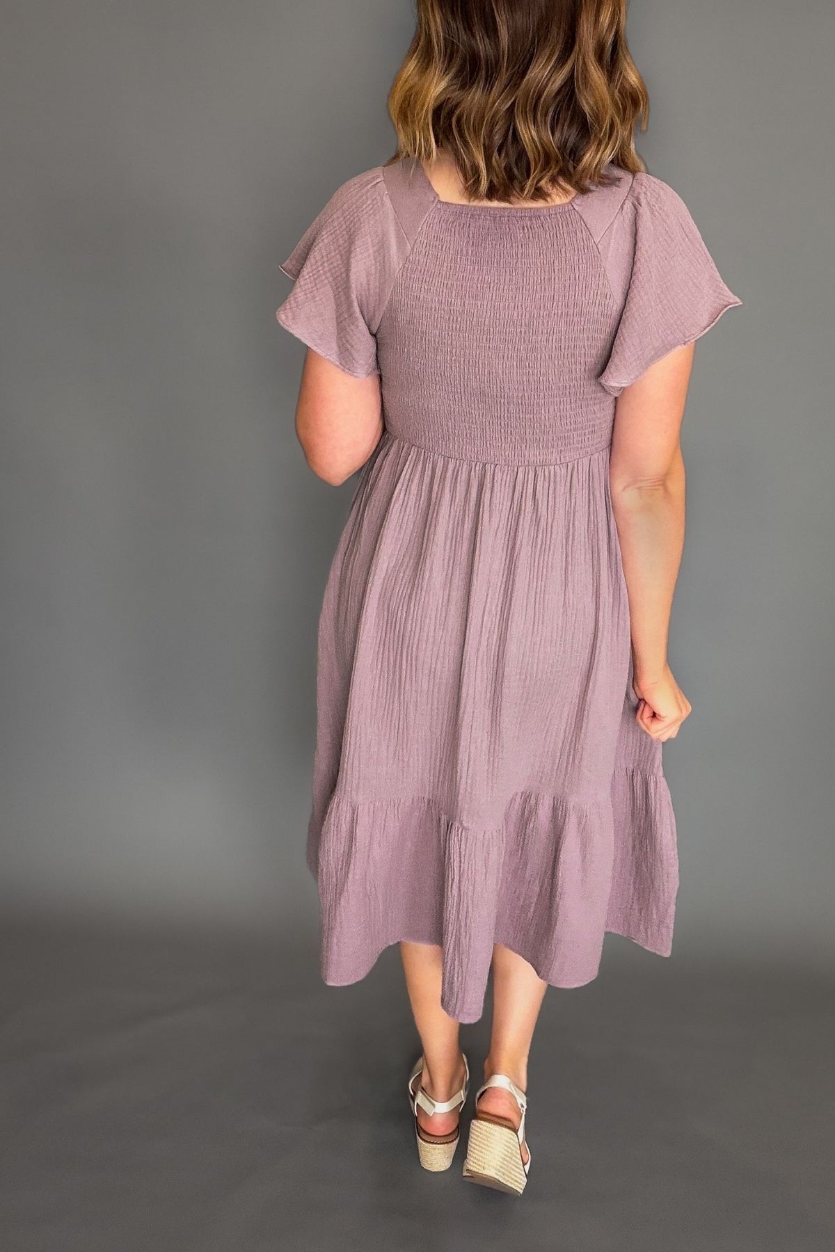 Woman wearing a mauve dress against a gray background
