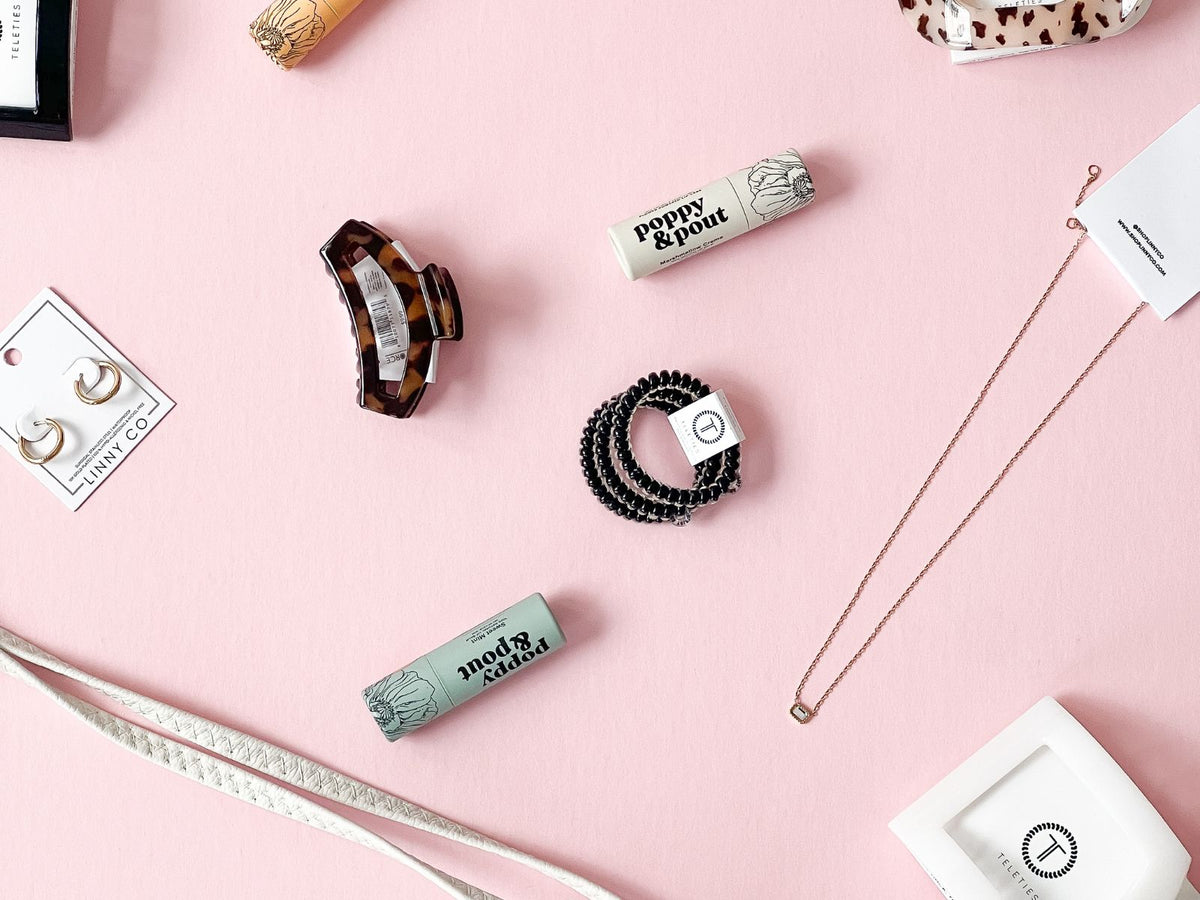 Collection of hair accessories and beauty products on a pink surface