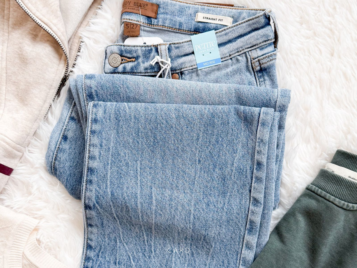 Folded blue jeans with a tag on a textured white surface
