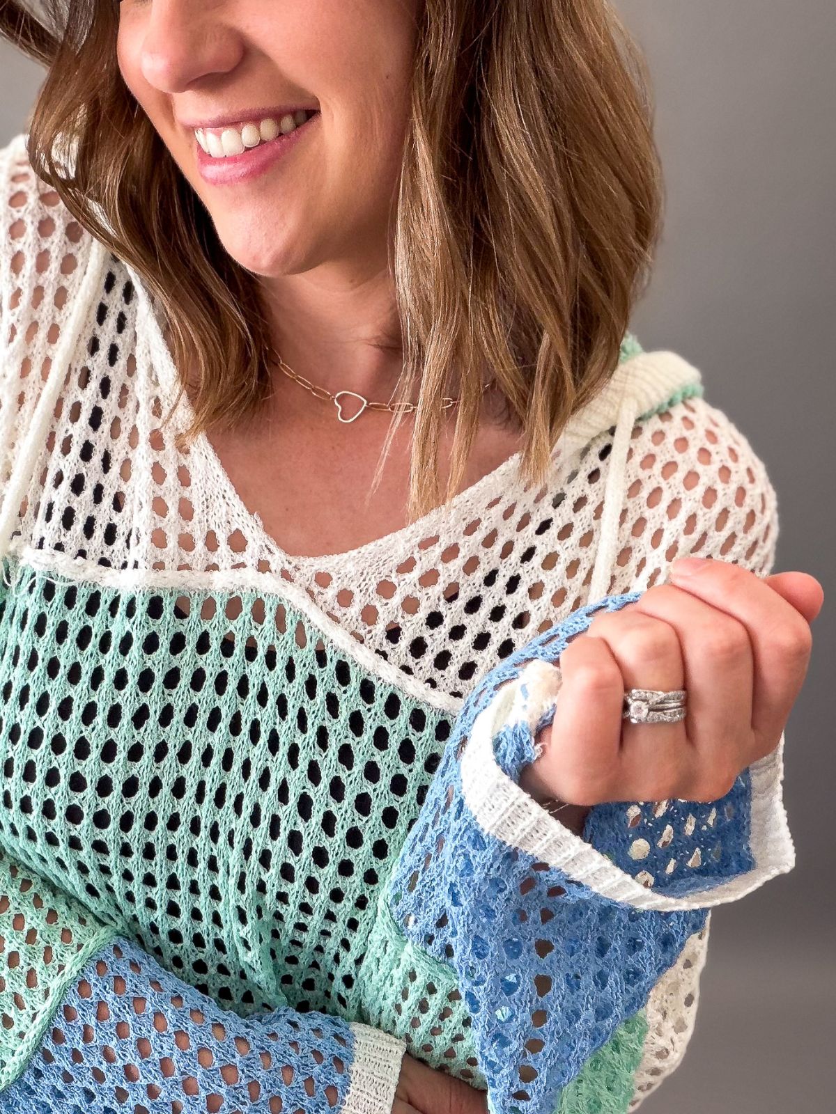 Woman wearing a colorful crochet top with a neutral background