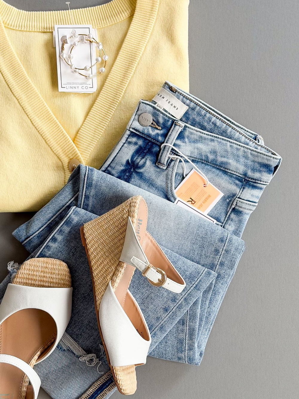 Yellow sweater, blue jeans, and white shoes on a gray surface