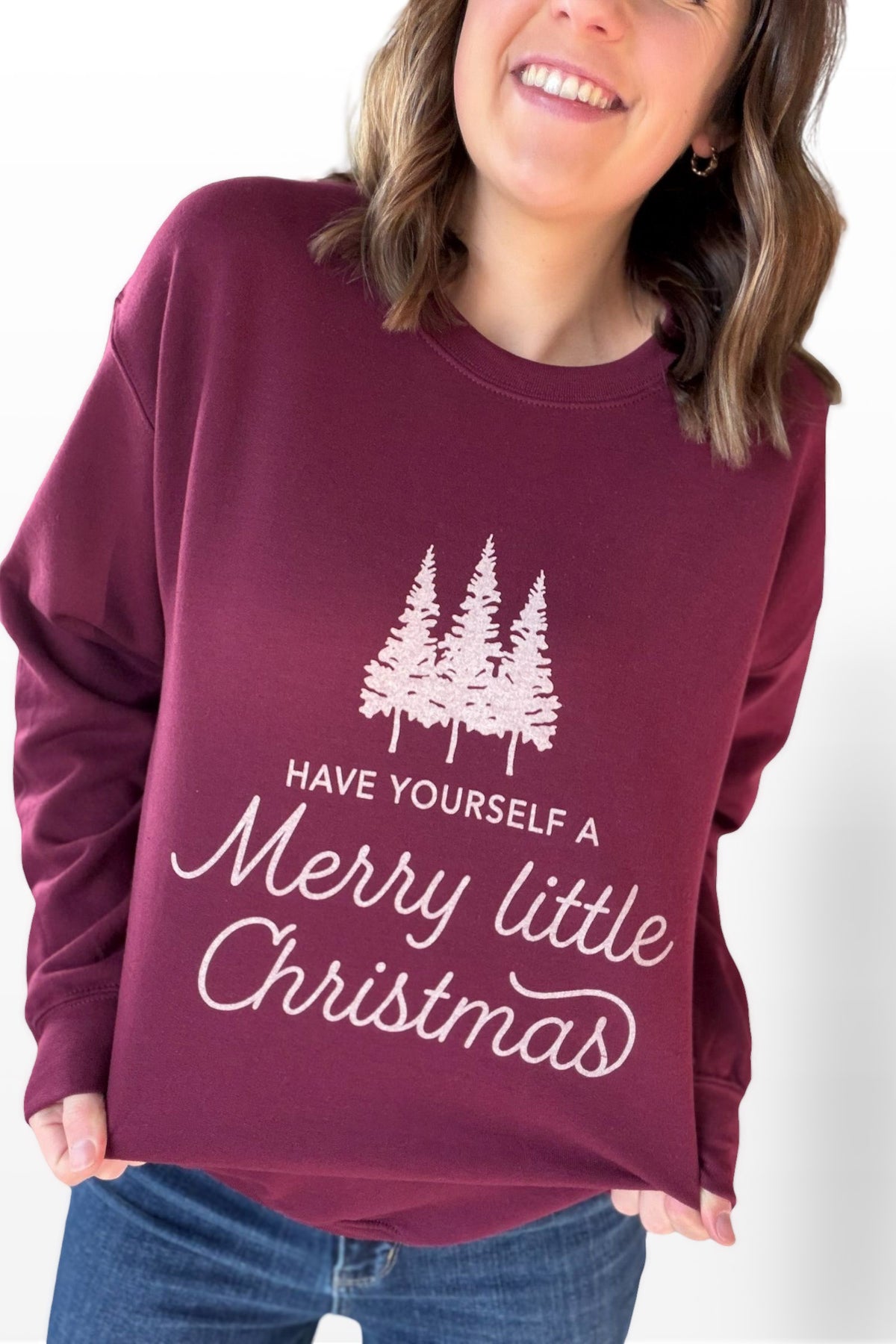 Person wearing a maroon sweatshirt with Christmas design and text.