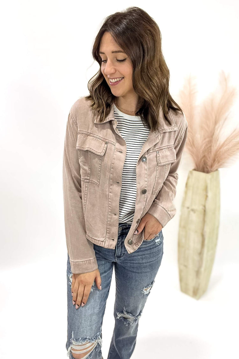 Woman wearing a dusty mauve jacket and blue jeans on a white background
