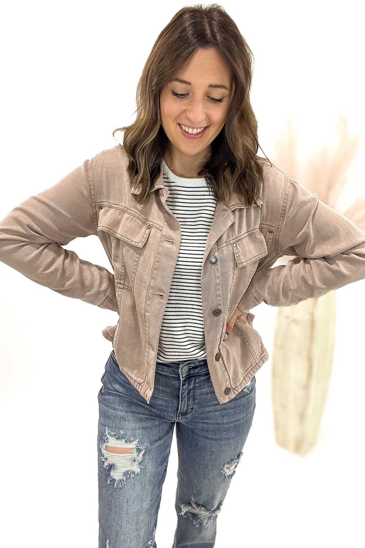 Woman wearing a dusty mauve denim jacket and blue jeans on a white background