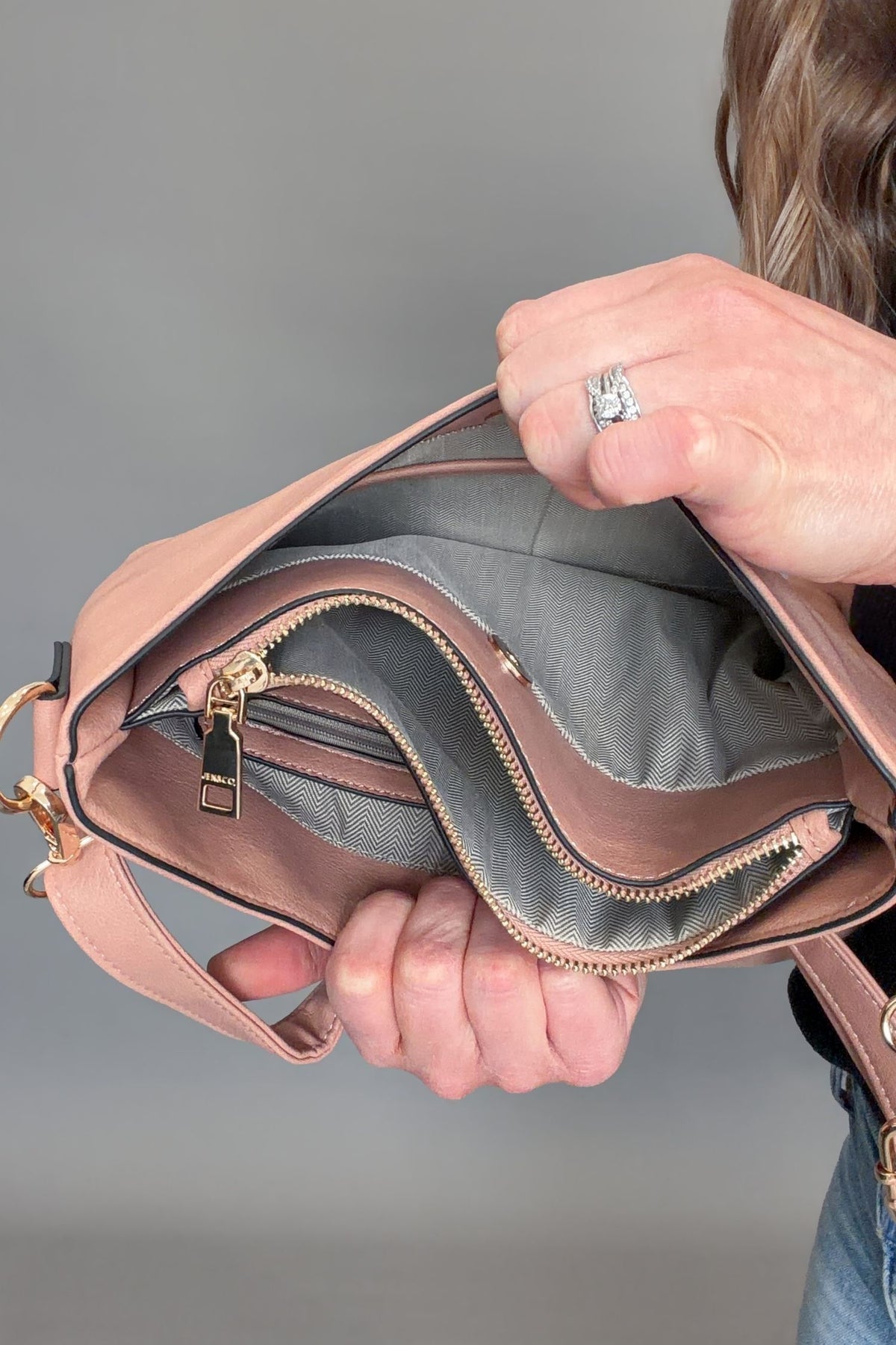Person holding a mauve handbag with a blurred gray background