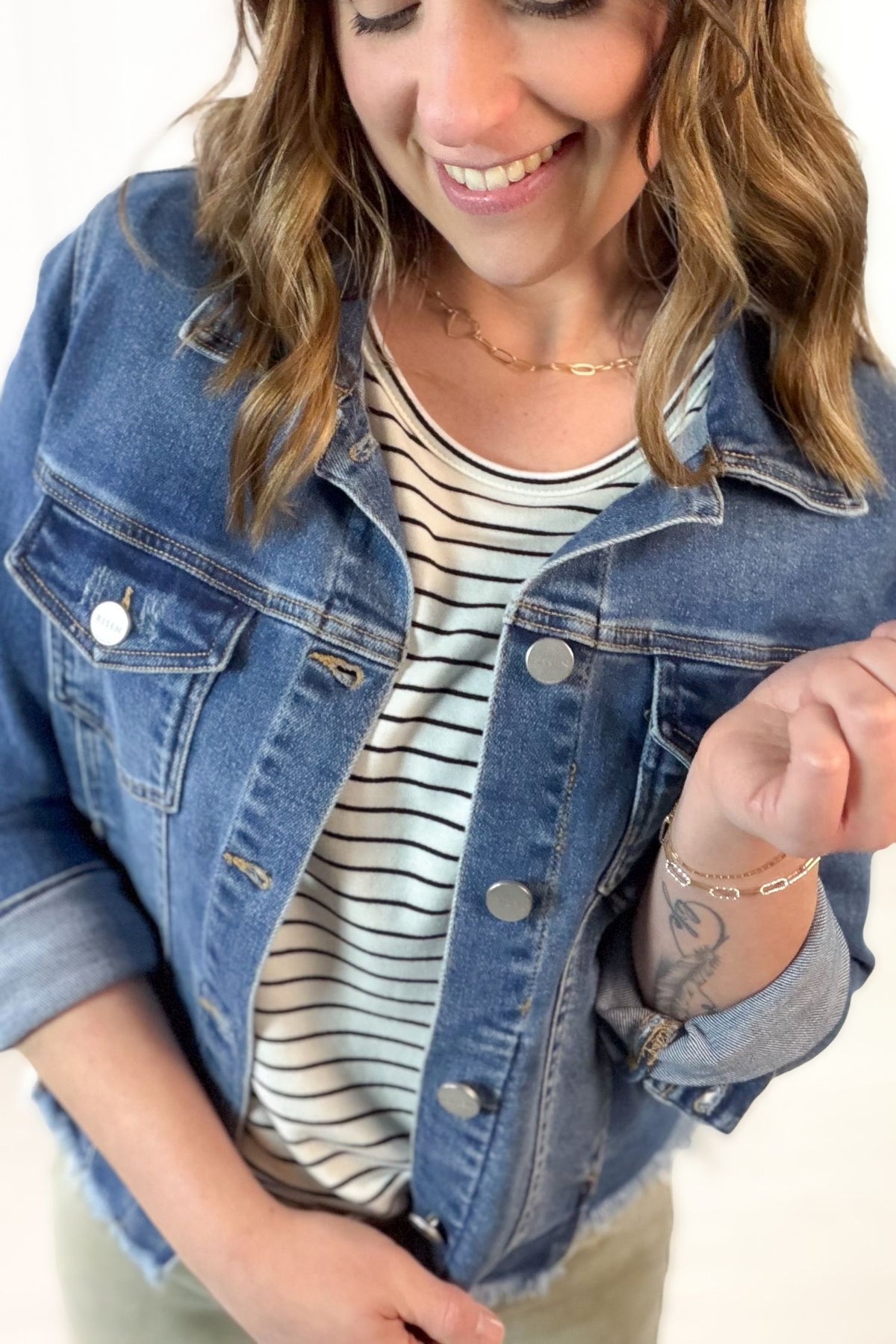 Woman wearing a denim jacket over a striped shirt with a neutral background