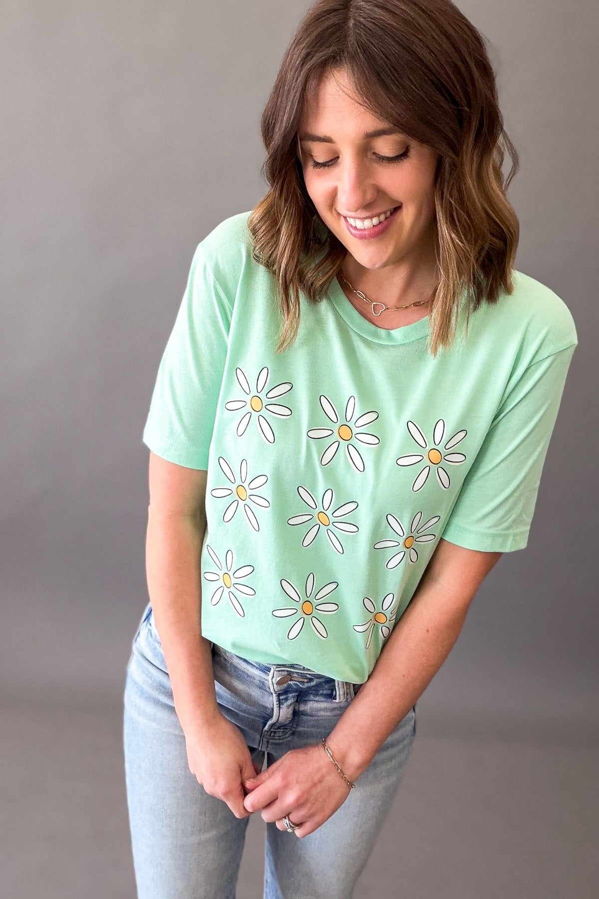 Woman wearing mint green daisy flower graphic tee with light