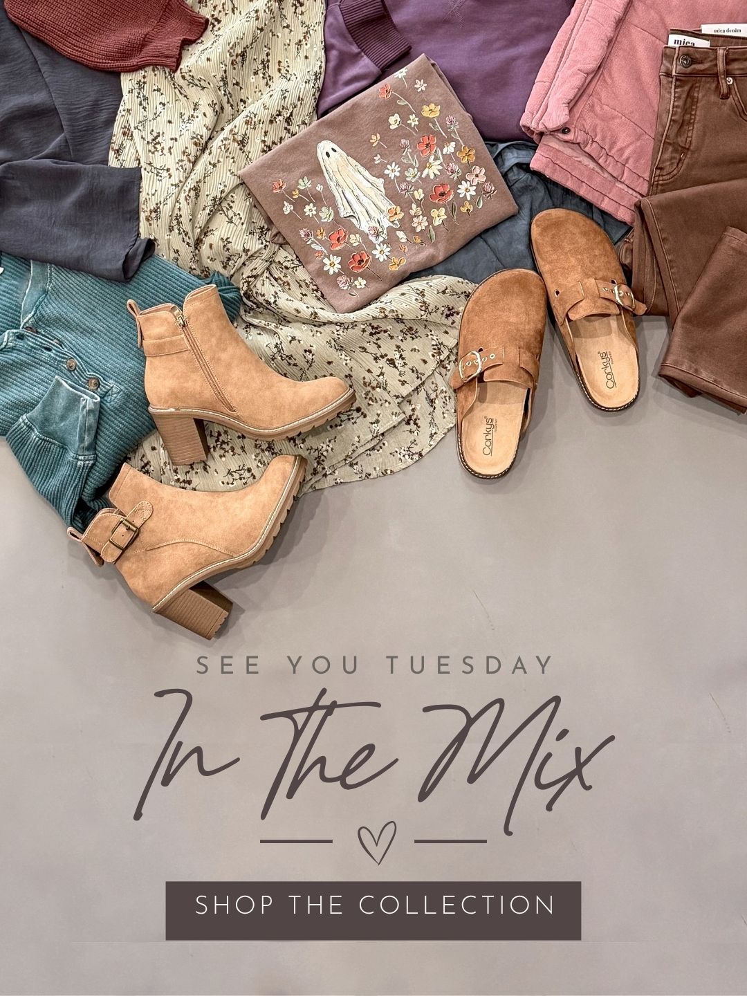 A styled flat-lay of multiple apparel and footwear items arranged on a gray surface, including tan ankle boots, brown mule sandals, a floral clutch, jeans, cardigans, and other clothing. Large overlaid text reads 'SEE YOU TUESDAY In The Mix' and 'SHOP THE COLLECTION'.