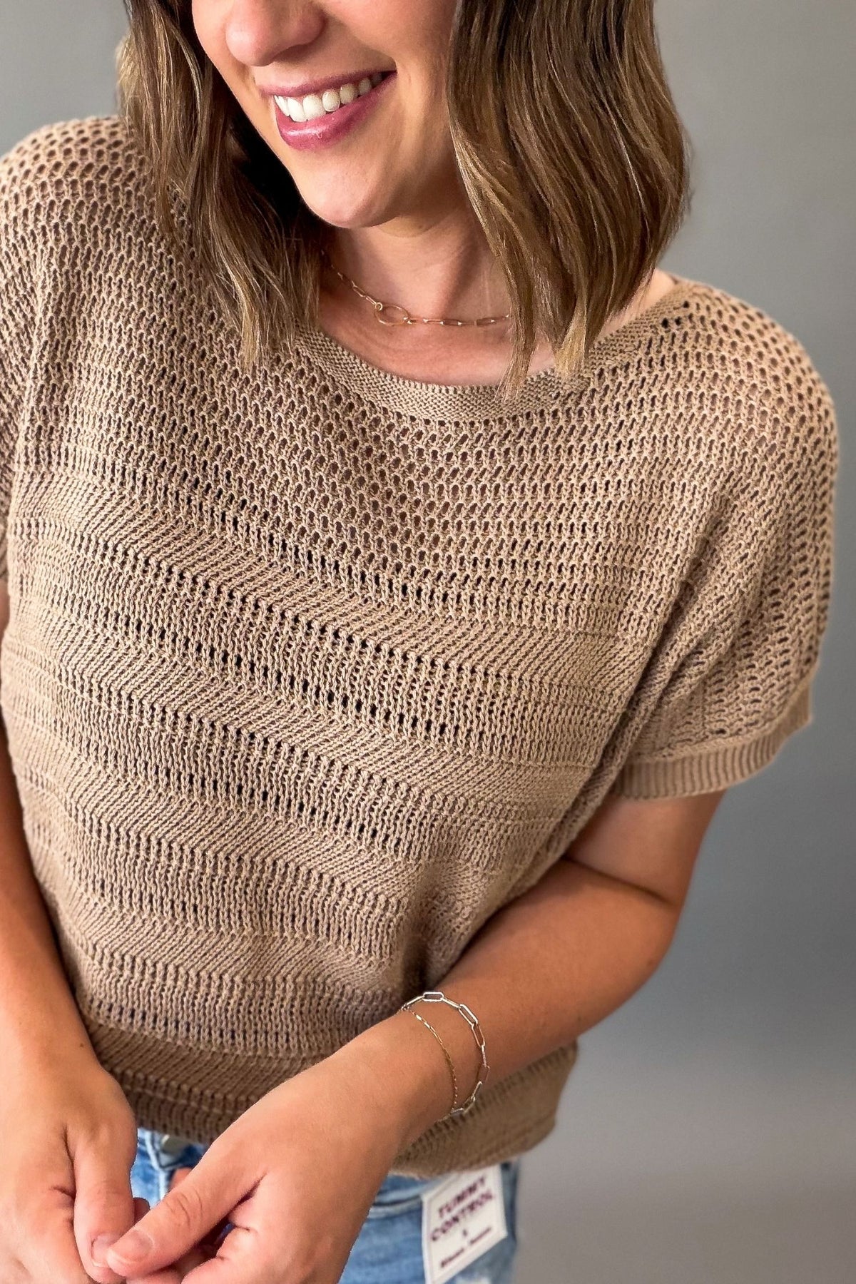 close up of a woman wearing a mocha crew neck short sleeve pointelle short sleeve sweater