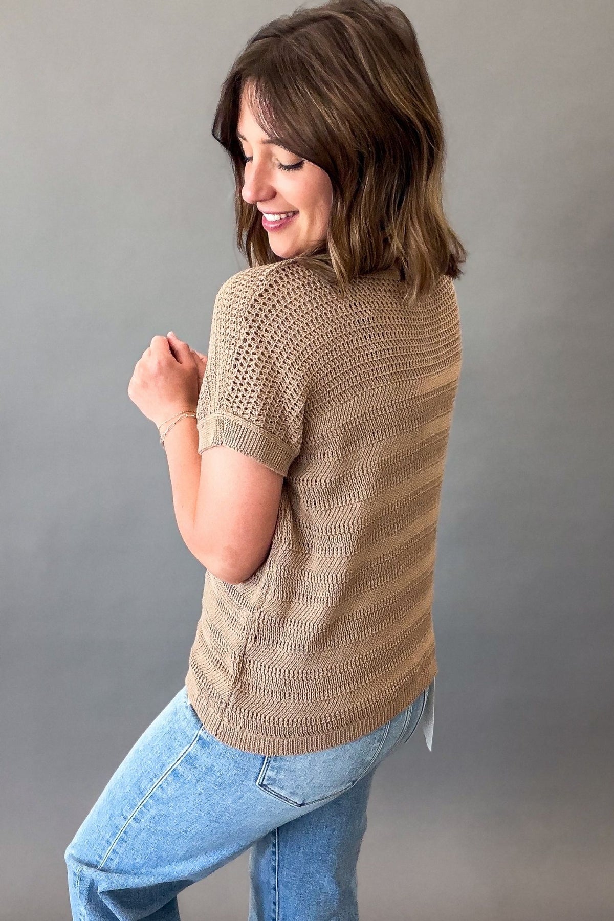 woman wearing a mocha crew neck short sleeve pointelle sweater showing the side and back details
