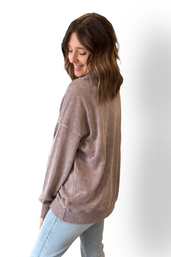 Woman wearing a mocha pullover and light blue jeans on a white background