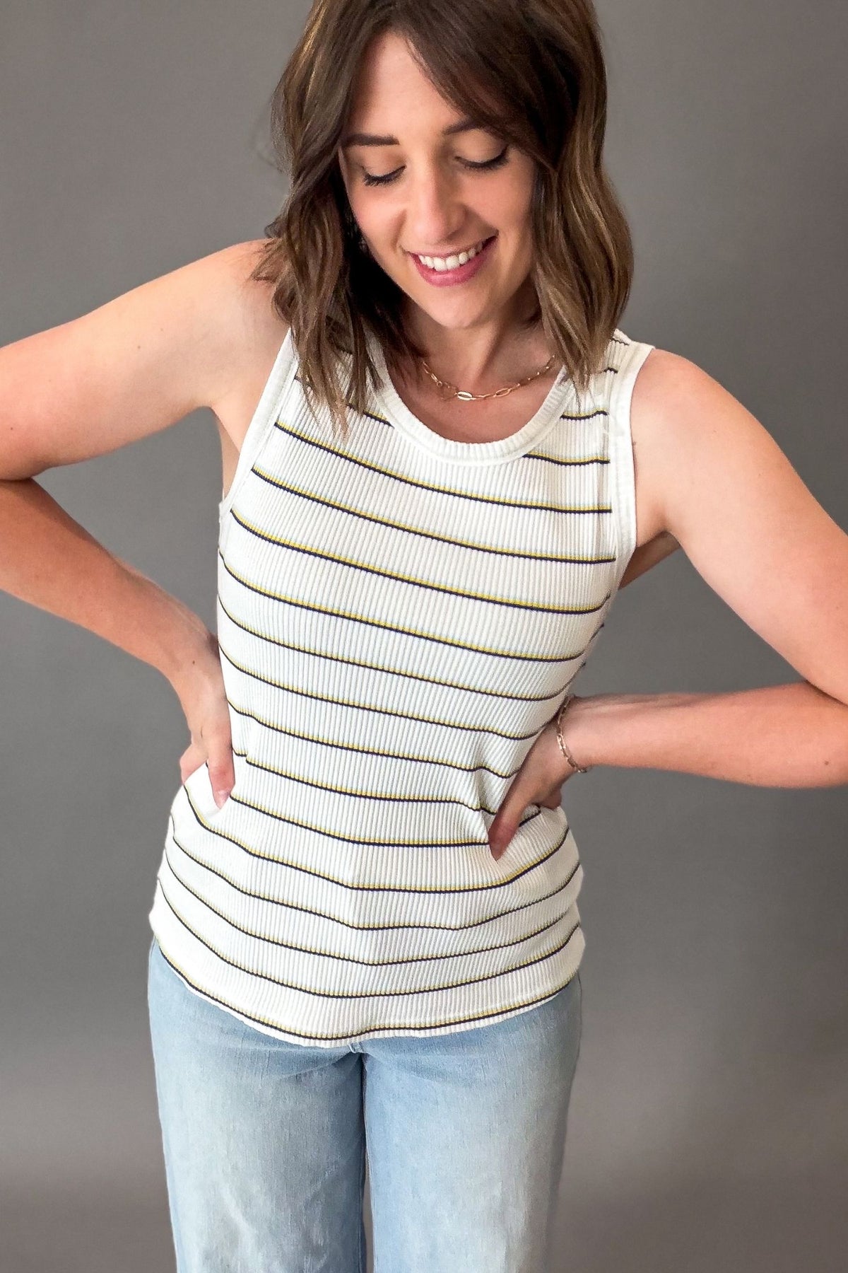 Woman wearing a striped tank top and jeans against a gray background