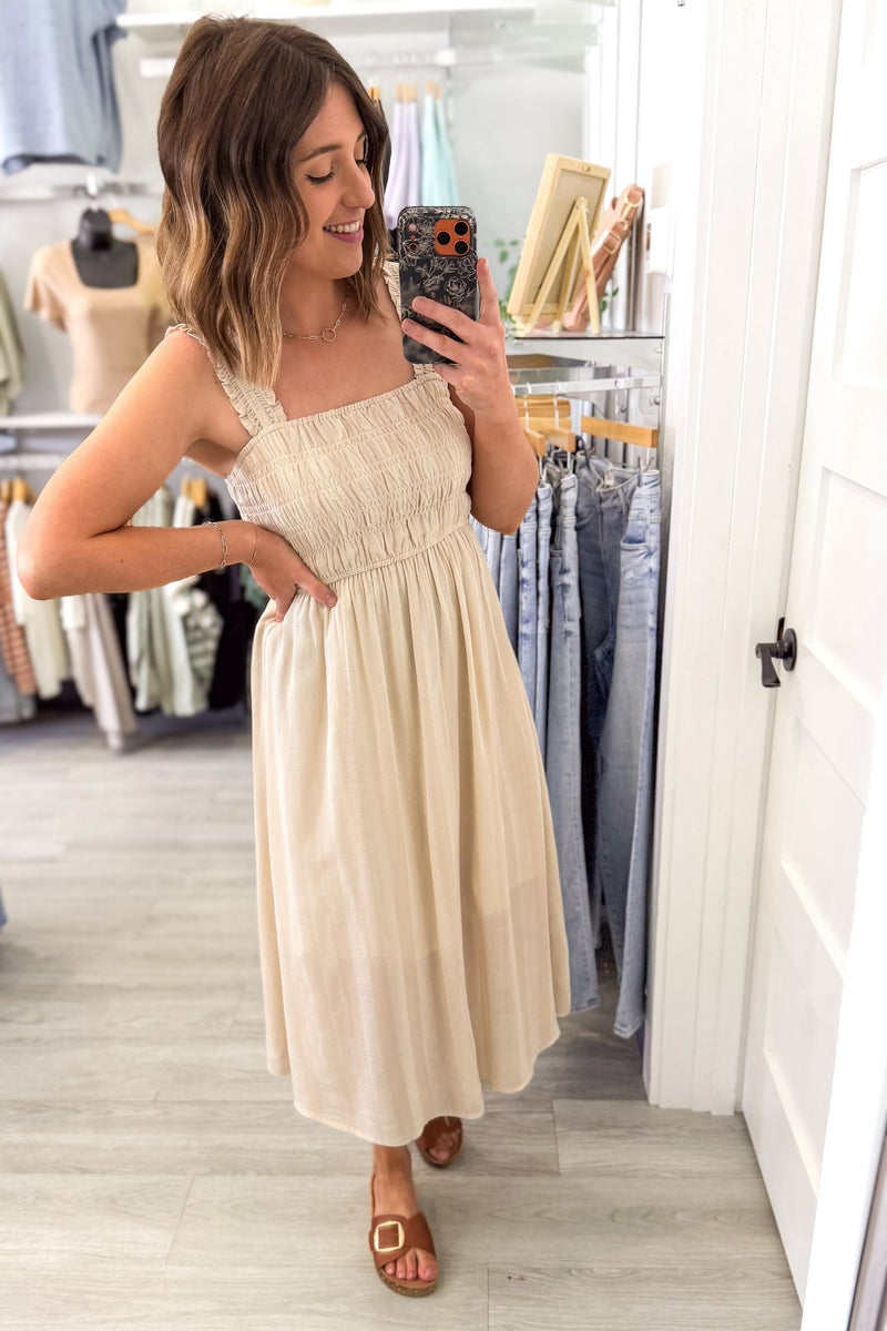woman taking a selfie in a boutique wearing a lightweight natural midi dress for family photos