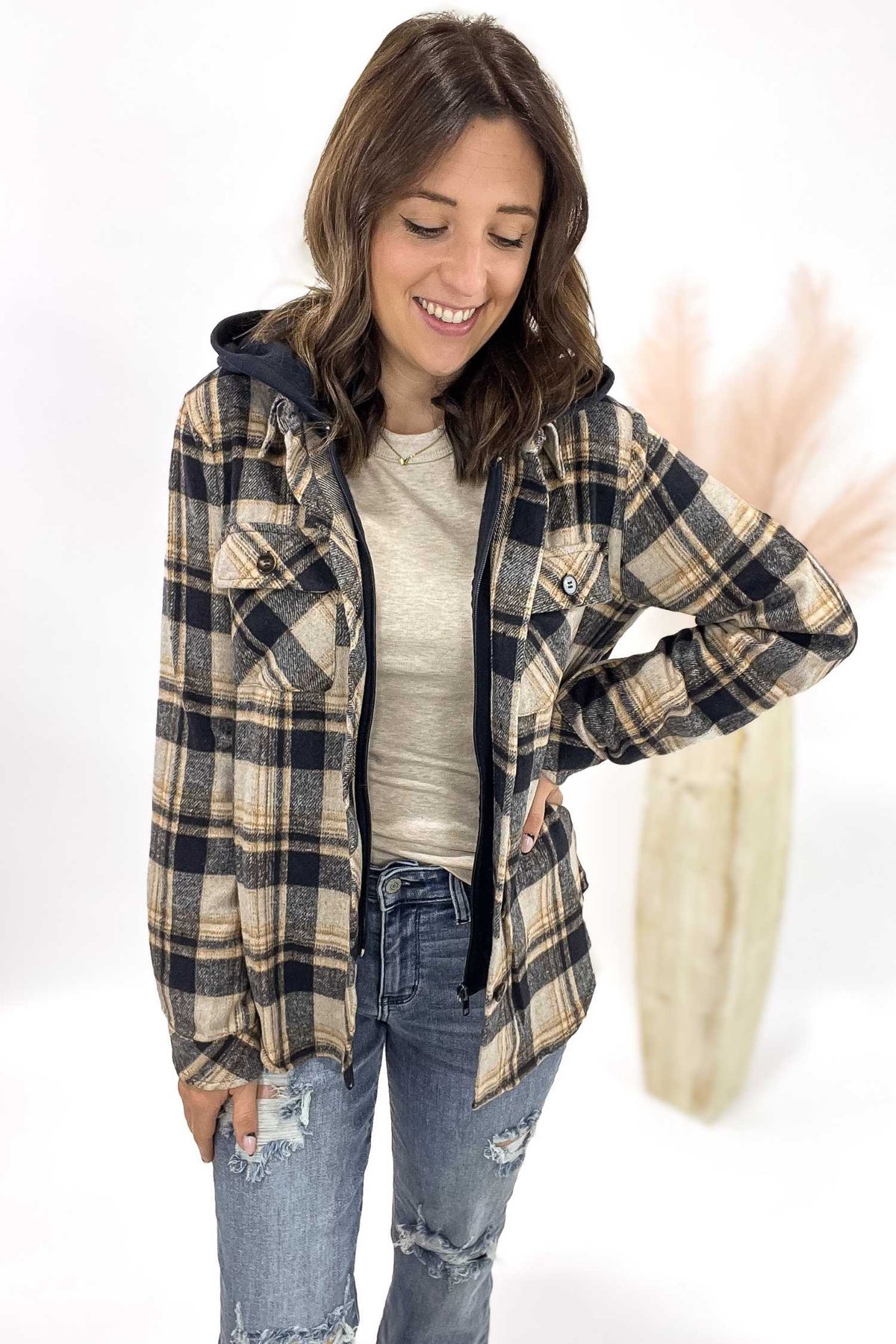 Woman wearing a plaid jacket with a hood on a white background