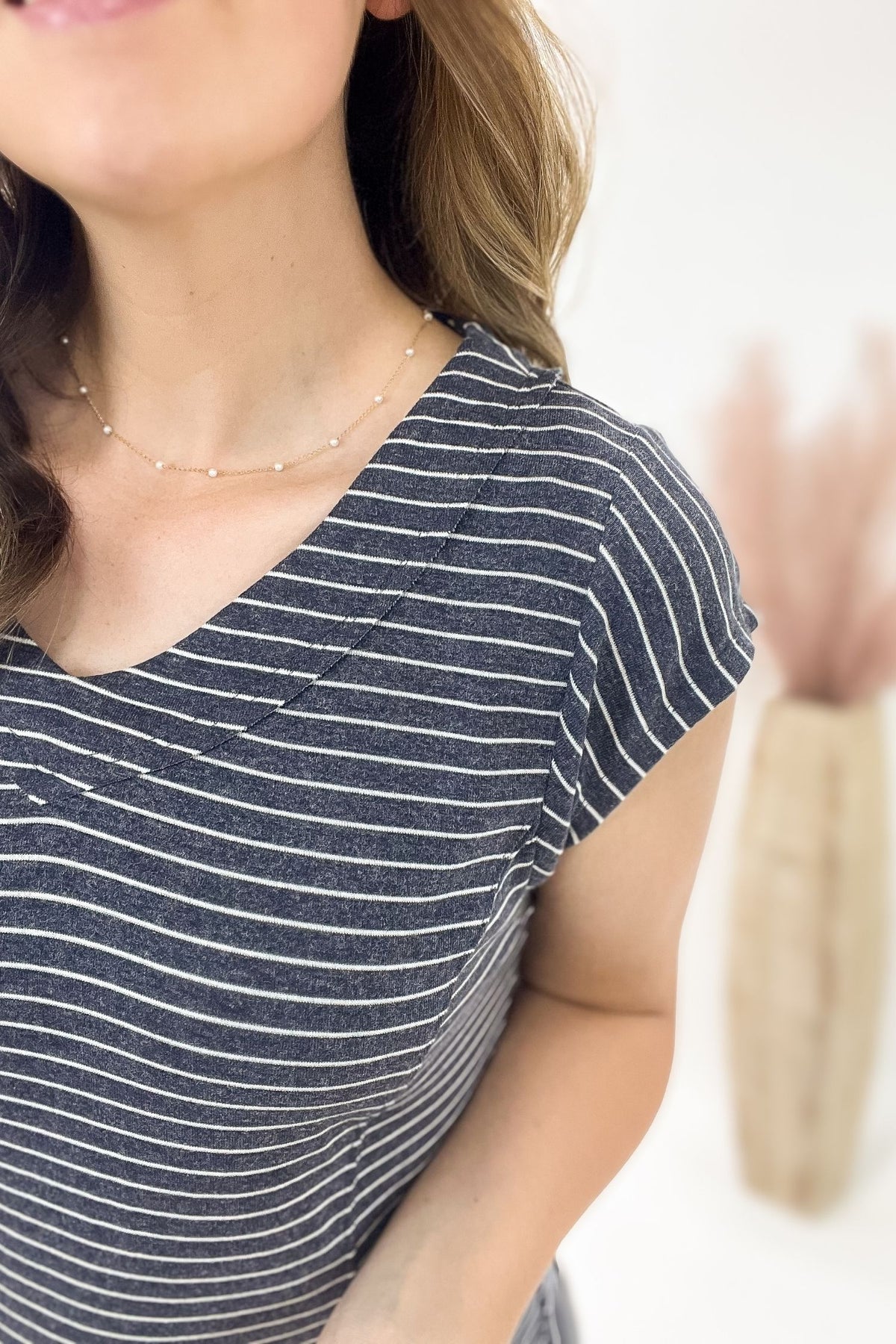 Woman wearing a navy and white striped shirt with a blurred background