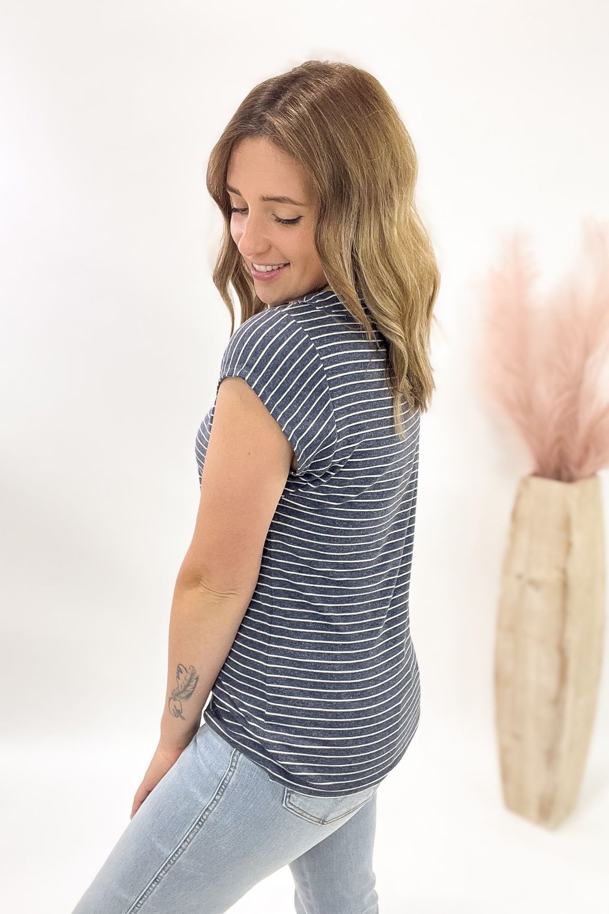 Woman wearing a striped shirt and jeans against a white background