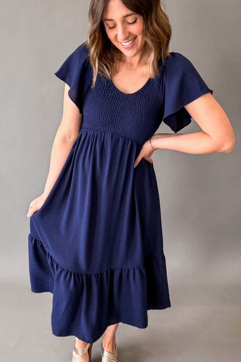 Woman wearing a navy blue dress against a gray background