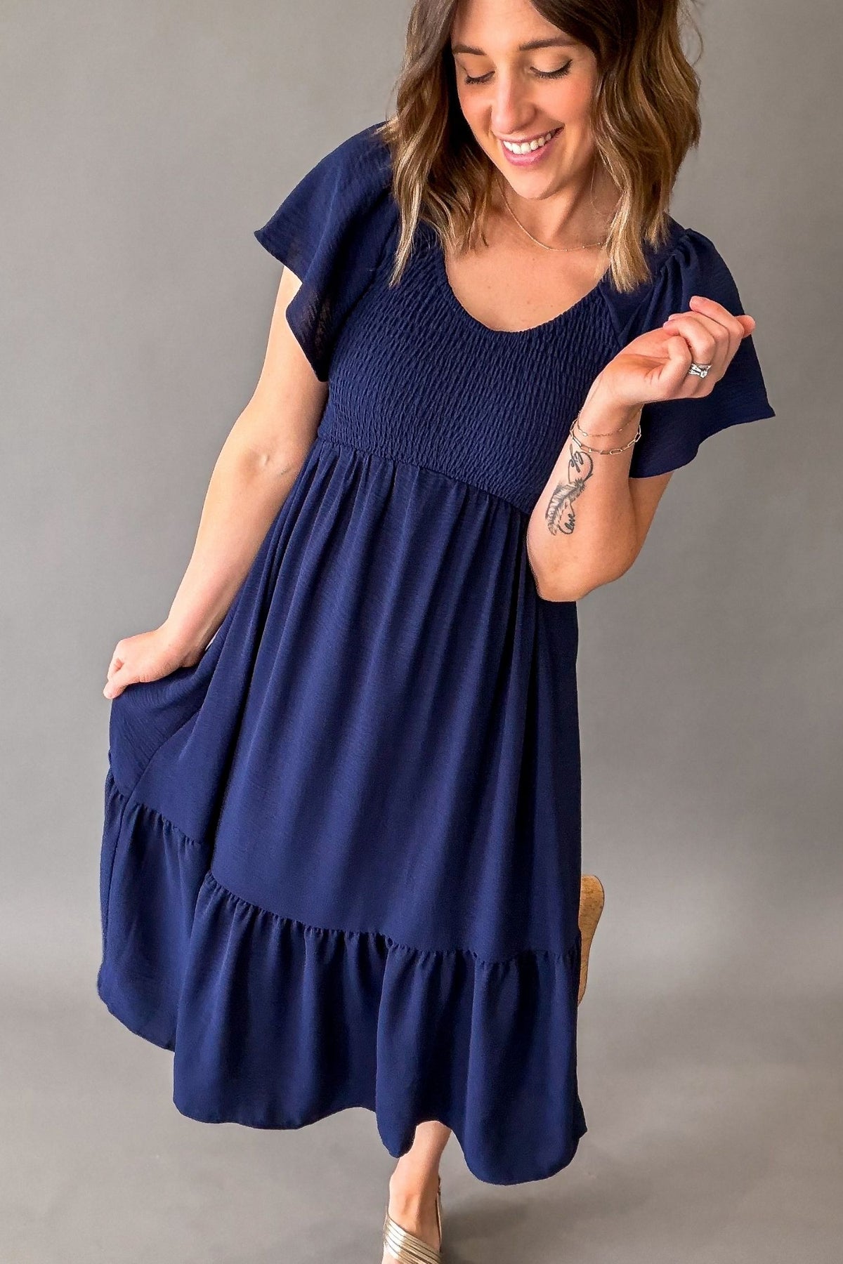 Woman wearing a navy blue dress against a gray background