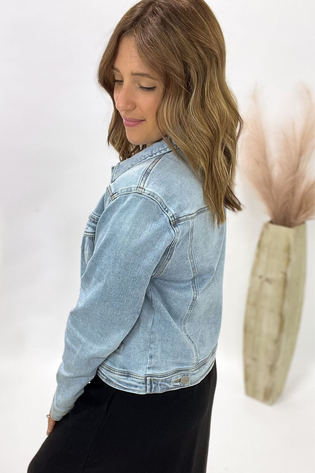 Woman wearing a light blue denim jacket against a white background